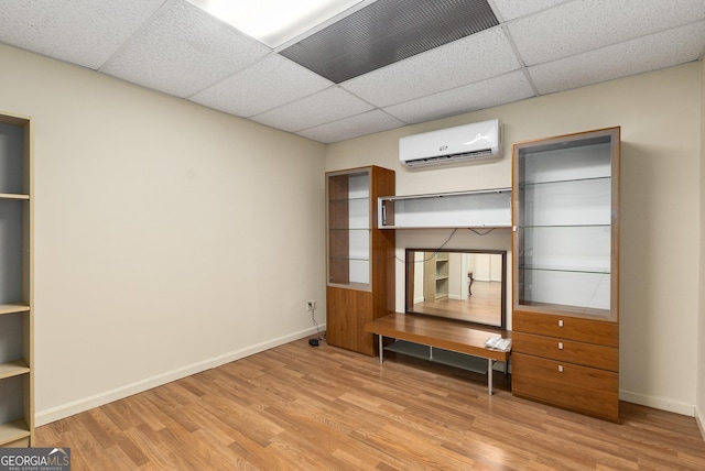 825 Yosemite Dr, Suwanee, GA 30024 - unfurnished bedroom with an AC wall unit, a drop ceiling, light wood-style flooring, and baseboards