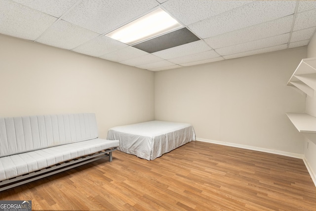 bedroom with light wood finished floors, baseboards, and a paneled ceiling