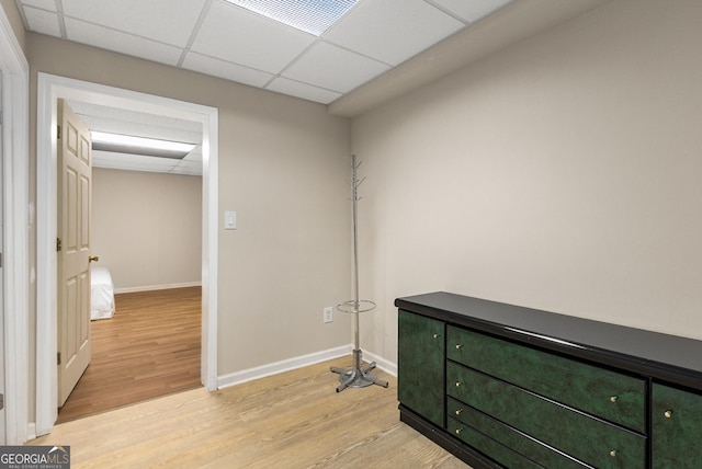 misc room with light wood finished floors, a drop ceiling, and baseboards