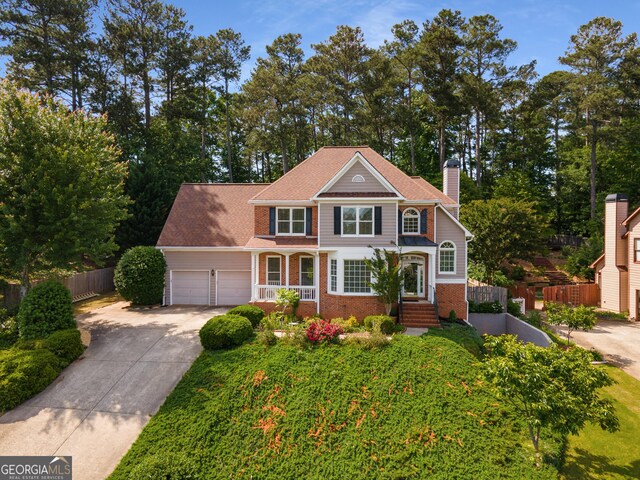 825 Yosemite Dr, Suwanee, GA 30024 - view of front of house featuring fence, brick siding, driveway, a chimney, and an attached garage