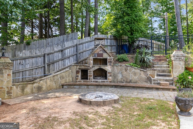 view of yard with an outdoor stone fireplace and fence