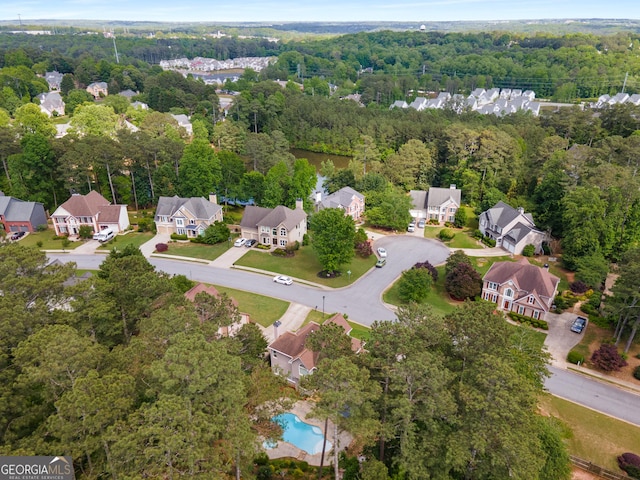 aerial view of property's location with a heavily wooded area, nearby suburban area, and a pool area