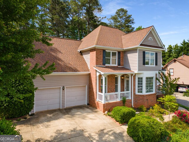 view of front of property featuring covered porch, concrete driveway, a garage, and brick siding