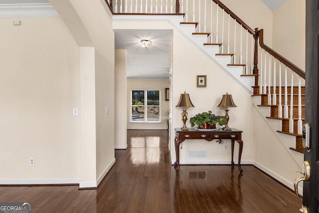 foyer with wood finished floors, baseboards, stairway, and crown molding