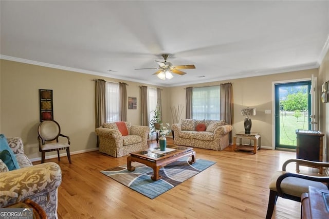 living area with crown molding, baseboards, ceiling fan, and light wood-style floors