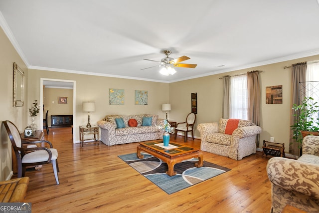 living area with wood finished floors, ceiling fan, crown molding, and baseboards