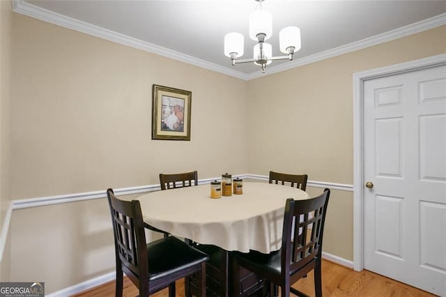 dining space featuring a chandelier, ornamental molding, light wood-type flooring, and baseboards