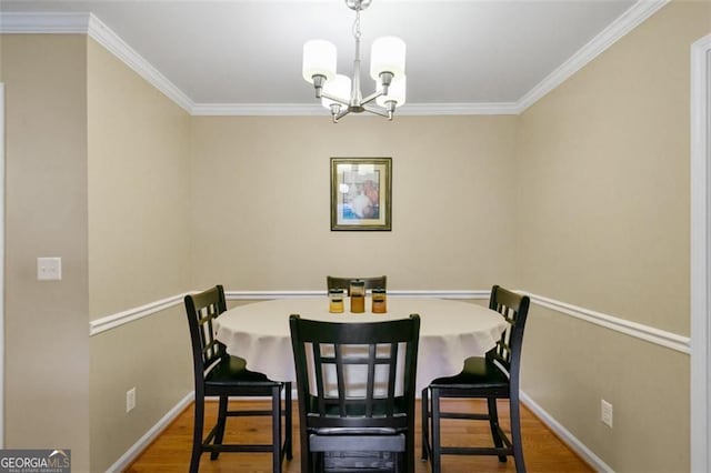 dining room with a chandelier, ornamental molding, wood finished floors, and baseboards