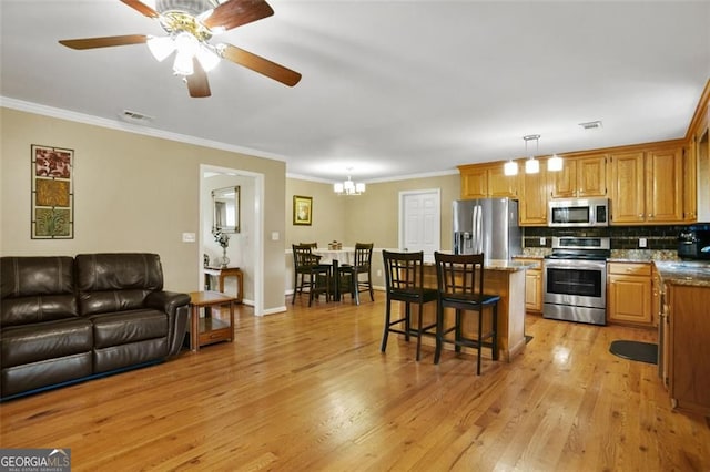 kitchen featuring stainless steel appliances, light wood-style floors, tasteful backsplash, a kitchen bar, and ornamental molding