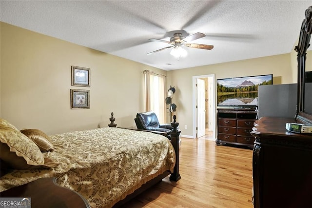 bedroom with light wood-style floors, a textured ceiling, a ceiling fan, and baseboards