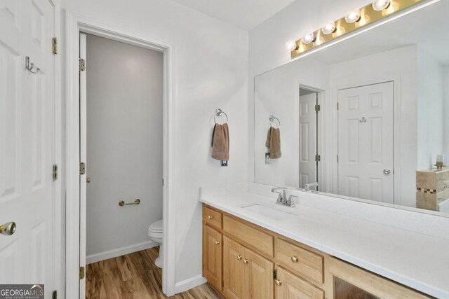 bathroom featuring toilet, wood finished floors, vanity, and baseboards