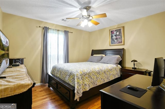 bedroom with wood finished floors, a desk, and ceiling fan