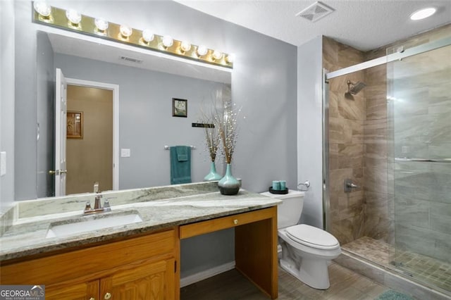 full bathroom featuring toilet, a shower stall, vanity, and a textured ceiling