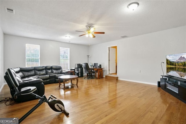 living room with an office area, light wood finished floors, ceiling fan, a textured ceiling, and baseboards