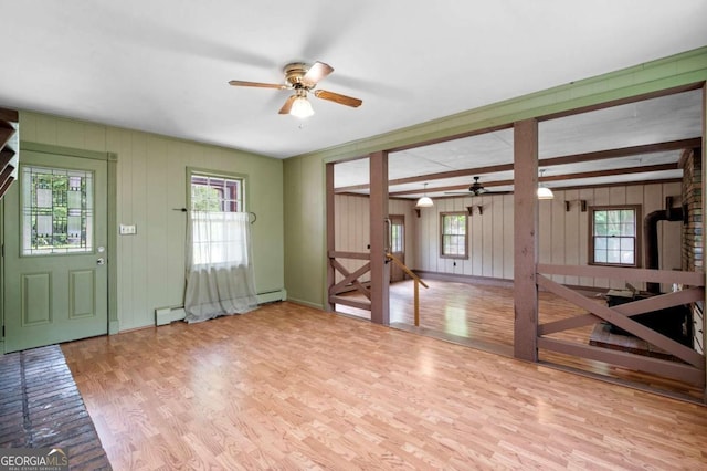 entrance foyer with a ceiling fan, wood finished floors, a baseboard heating unit, and wood walls