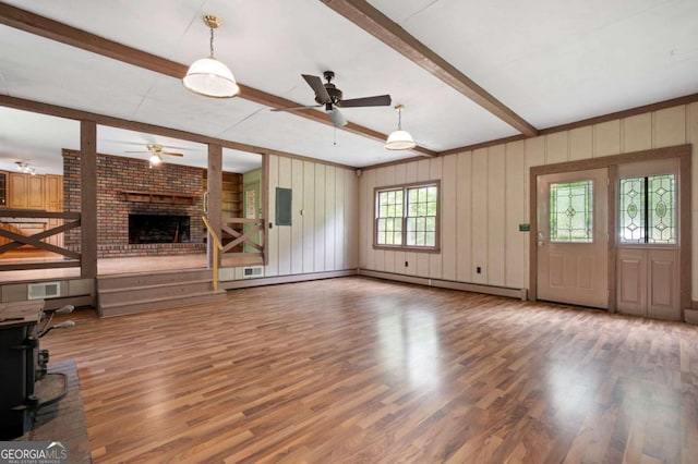 unfurnished living room featuring a ceiling fan, beam ceiling, wood finished floors, and a fireplace