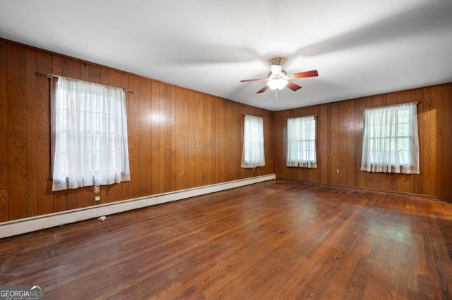 empty room featuring a baseboard heating unit, a ceiling fan, and wood finished floors
