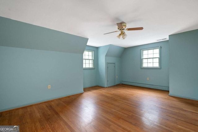 bonus room with a baseboard heating unit, wood finished floors, ceiling fan, baseboards, and lofted ceiling