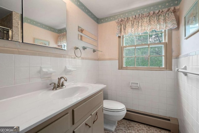 bathroom with a baseboard heating unit, healthy amount of natural light, toilet, tile walls, and vanity