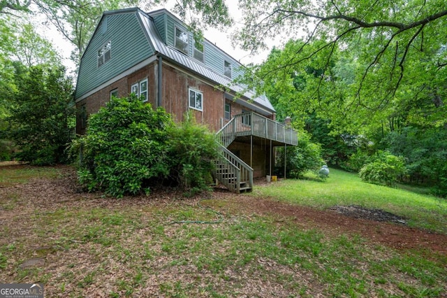 back of house with stairway, a deck, metal roof, a gambrel roof, and a lawn