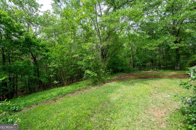view of green lawn with a wooded view
