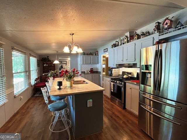 317 Cedar Dr NW, Sparta, GA 31087 - kitchen with stainless steel appliances, dark wood-style flooring, under cabinet range hood, a chandelier, and a kitchen island with sink