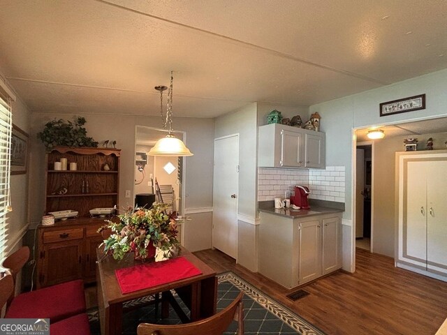 317 Cedar Dr NW, Sparta, GA 31087 - kitchen with dark wood-type flooring, backsplash, dark countertops, and pendant lighting