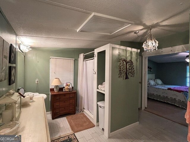 317 Cedar Dr NW, Sparta, GA 31087 - ensuite bathroom with wood finished floors, a textured ceiling, curtained shower, a chandelier, and baseboards