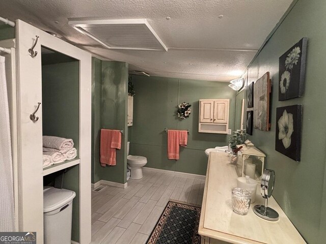 317 Cedar Dr NW, Sparta, GA 31087 - bathroom with toilet, a textured ceiling, wood tiled floors, baseboards, and vanity