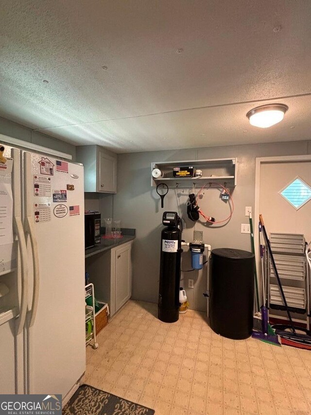 317 Cedar Dr NW, Sparta, GA 31087 - kitchen with white fridge with ice dispenser, light flooring, dark countertops, a textured ceiling, and black microwave