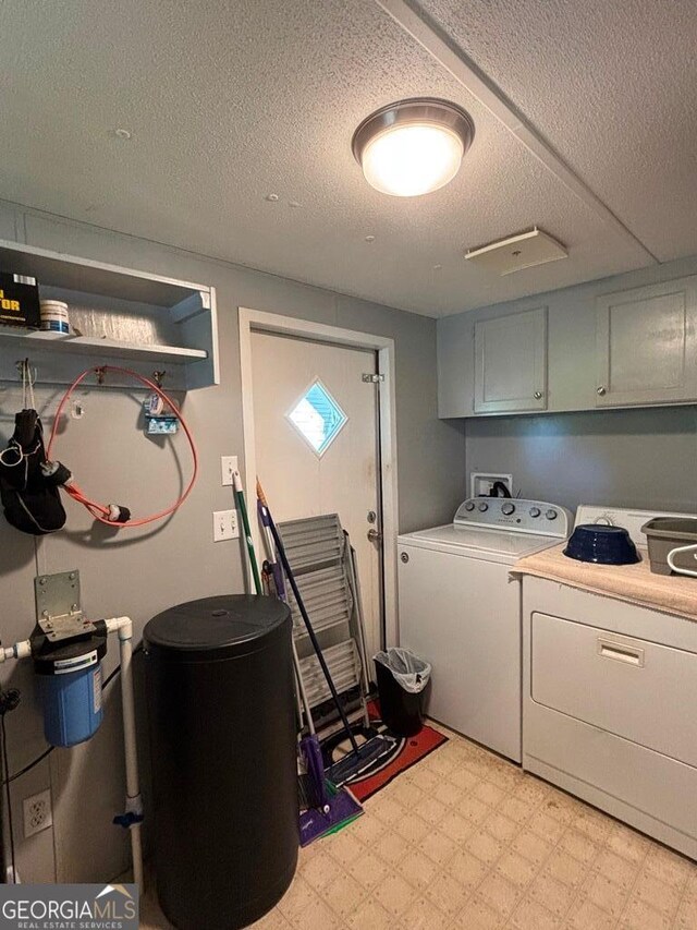 317 Cedar Dr NW, Sparta, GA 31087 - clothes washing area featuring cabinet space, washing machine and dryer, a textured ceiling, and light floors