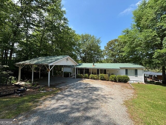 317 Cedar Dr NW, Sparta, GA 31087 - view of front of home with gravel driveway, a front lawn, a detached carport, and metal roof