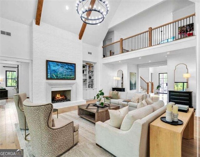 1592 Howell Bridge Rd, Ball Ground, GA 30107 - living area featuring an inviting chandelier, a warm lit fireplace, high vaulted ceiling, and visible vents