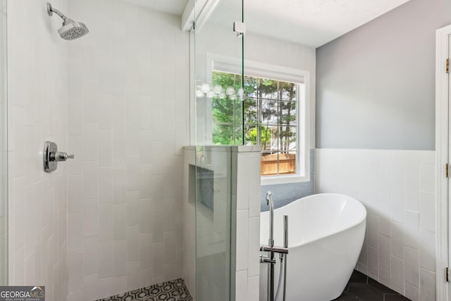 7675 Rose Ln, Cumming, GA 30040 - bathroom with a stall shower, a freestanding bath, tile walls, and a wainscoted wall