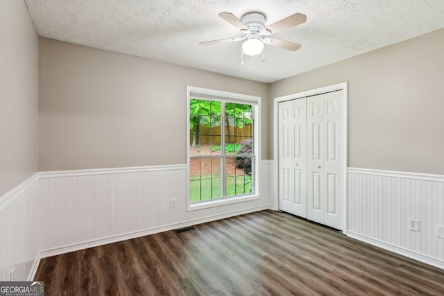 7675 Rose Ln, Cumming, GA 30040 - unfurnished bedroom featuring wainscoting, wood finished floors, a textured ceiling, a closet, and ceiling fan