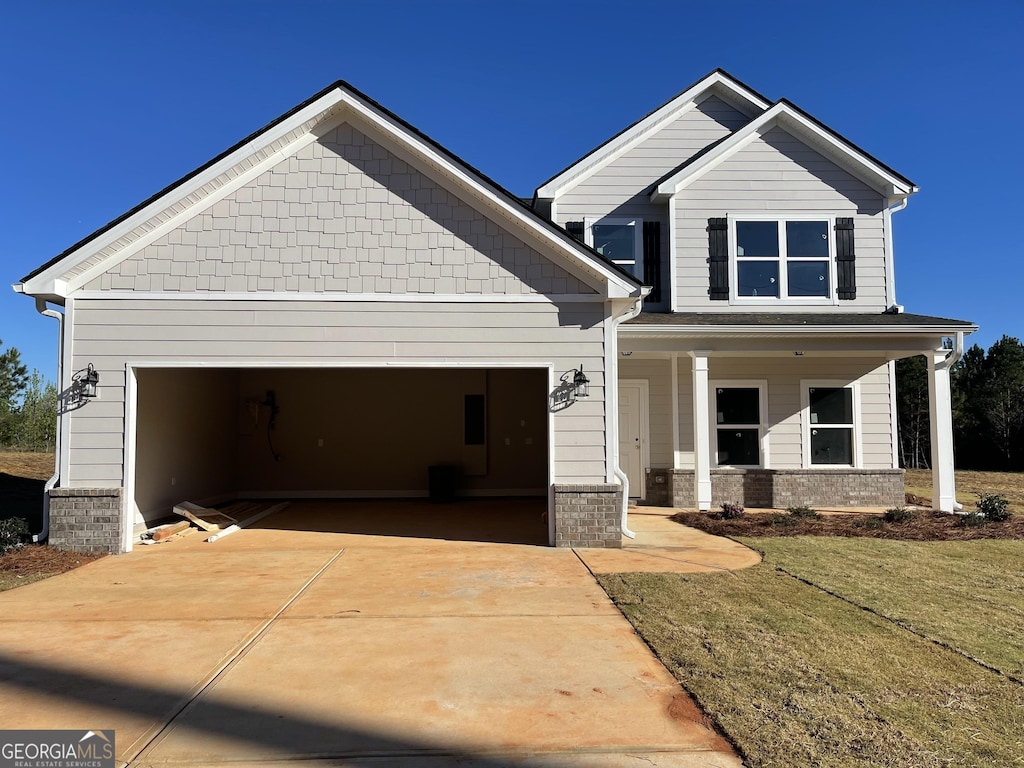 craftsman house with an attached garage, concrete driveway, a front lawn, and a porch