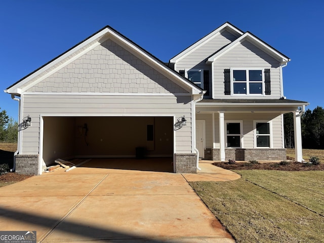 craftsman house with an attached garage, concrete driveway, a front lawn, and a porch