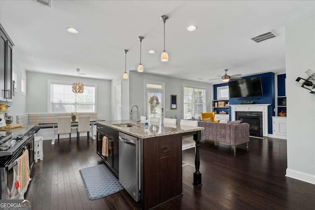 kitchen featuring a sink, a breakfast bar area, appliances with stainless steel finishes, a high end fireplace, and a ceiling fan