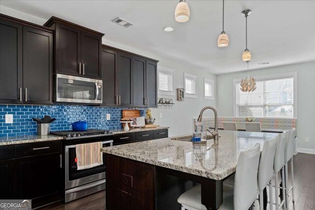 kitchen featuring appliances with stainless steel finishes, a sink, dark wood finished floors, a kitchen island with sink, and recessed lighting