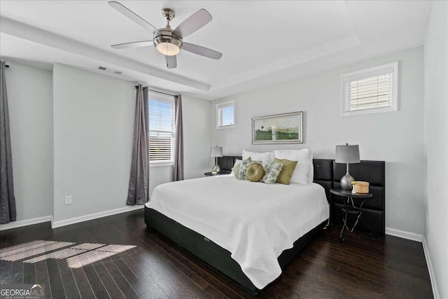 bedroom featuring a raised ceiling, baseboards, and wood finished floors