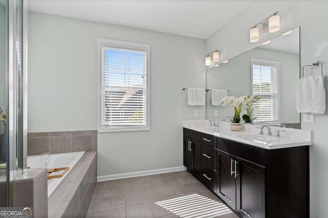 bathroom with a bath, tile patterned floors, double vanity, and baseboards