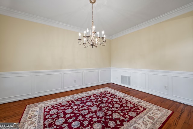 dining room with a chandelier, crown molding, wood finished floors, and wainscoting