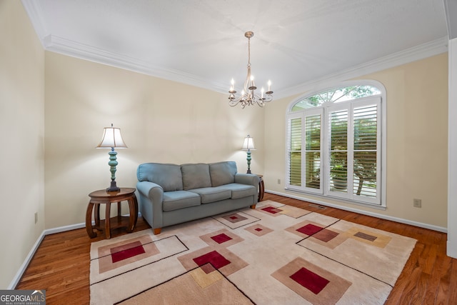 living room featuring wood finished floors, ornamental molding, a chandelier, and baseboards