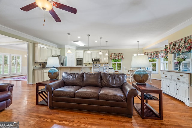 living room with light wood finished floors, crown molding, and a ceiling fan