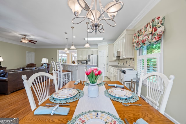 dining space with a ceiling fan, light wood-type flooring, ornamental molding, and a chandelier
