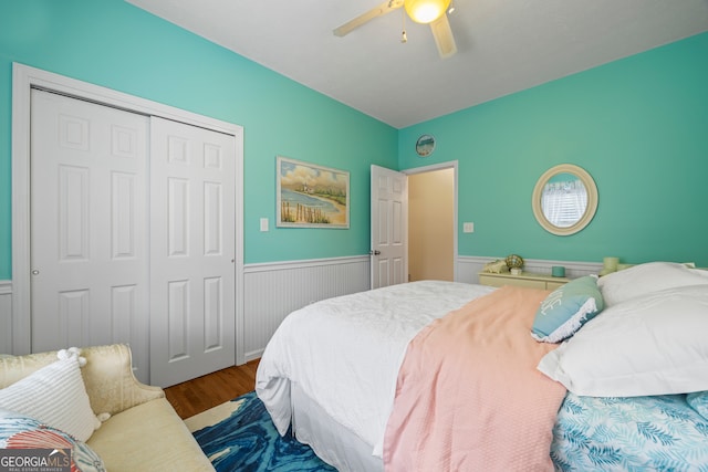 bedroom with wainscoting, a closet, wood finished floors, and a ceiling fan