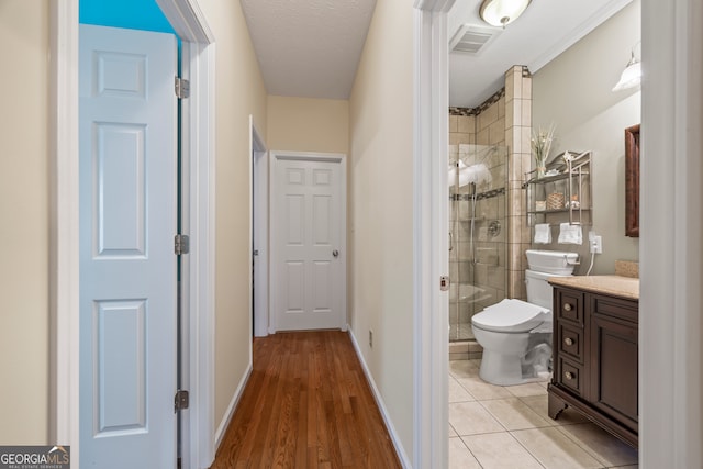 bathroom with toilet, a shower stall, vanity, baseboards, and wood finished floors