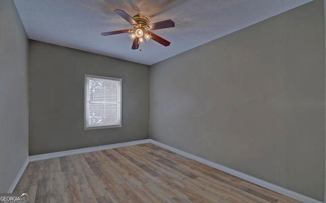 empty room with wood finished floors, baseboards, ceiling fan, and a textured ceiling