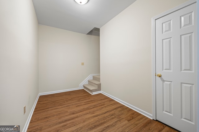 unfurnished room with wood finished floors, baseboards, and stairs