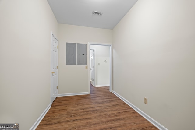 corridor featuring dark wood-type flooring, baseboards, and electric panel